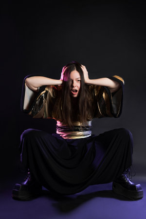 Stylish and daring image, futuristic fashion. A young woman in a multicultural outfit mixing Asian and European style, a golden kimono shirt and trousers, photo in the studio on blackの写真素材
