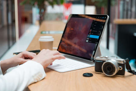 A freelance photographer works remotely, a thin mobile computer with a photo on the screen and a camera in the foreground. Creative work, retouching or creating designs.の写真素材