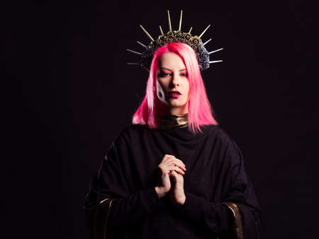 A gothic diva with pink hair in a royal image, a crown with roses and rays on her head, hands folded in a prayer gesture.の写真素材