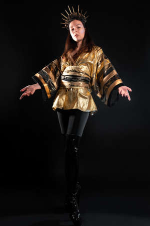 A sorceress in a golden shirt in Asian style, a gothic image of a mixture of cultures and styles, a young woman in gold with a crown with rays on her headの写真素材