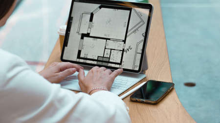 An architect engineer works remotely, freelance work on a laptop, concept. A device with a floor plan on the screen, hands on the keyboard, close-upの写真素材