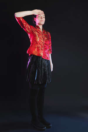 Young woman in a red shirt in Chinese style, photo in the studio on a black backgroundの写真素材