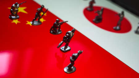 The concept of the economic and political crisis between Japan and China, toy soldiers attacking each other against the background of national flags.の写真素材