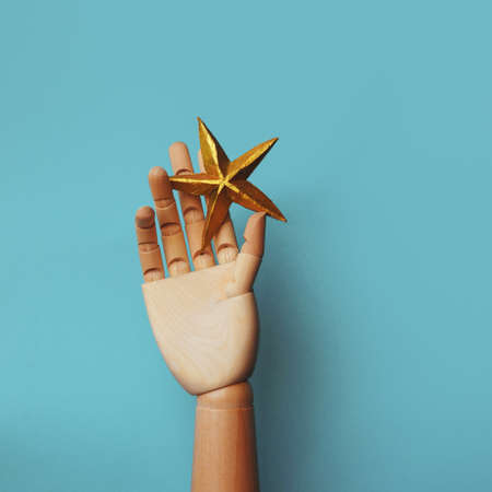 A star in your hand, striving for a dream. Gold star in a wooden hand, a prize for achieving goals,...