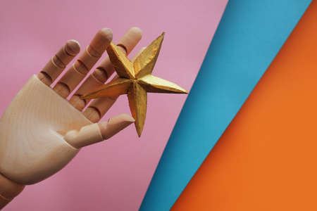 A star in your hand, striving for a dream. Gold star in a wooden hand, a prize for achieving goalsの写真素材