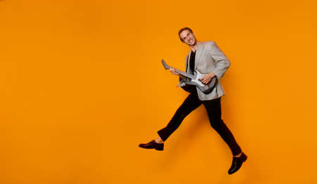 rock  n  roll guy, a cool guy with a fake guitar, pretends to play music. Fun and emotion. A guy in a jacket with a gaming guitar, playing guitar in a simulator. Copy the space on the leftの写真素材