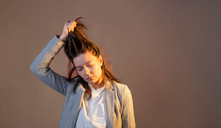 How to pull yourself out of depression. Solve your problems with an effort of will. A young tired woman pulls her hair, the concept of solve your problems by yourselfの写真素材