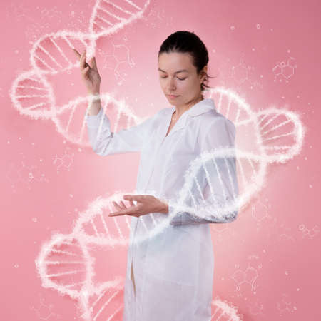 DNA, genome research, concept. A young female scientist in a white coat holds a DNA molecule in front of herの写真素材
