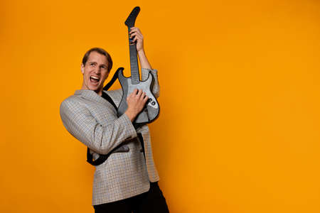 rock  n  roll guy, a cool guy with a fake guitar, pretends to play music. Fun and emotion. A guy in a jacket with a gaming guitar, playing guitar in a simulatorの写真素材