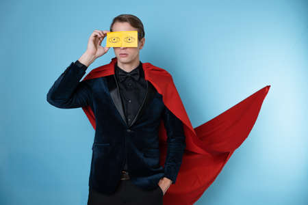 Sleep problems due to overwork. A man in a business suit and a red cape like a superhero with cartoon eyes over closed eyesの写真素材