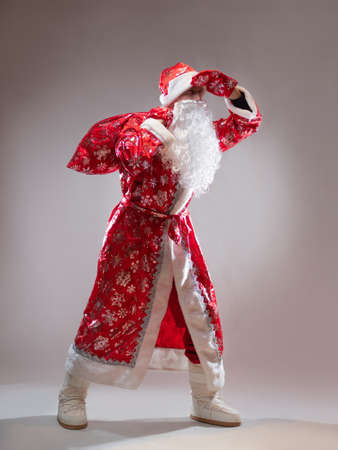 Santa Claus with a bag of gifts looks forward to celebrating the New year,a holiday for children, New Years gifts, in full growth on a gray backgroundの写真素材
