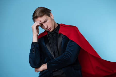 Impostor syndrome in professionals, concept. superhero feels tired and insecure. A man in a business suit and a red cape.の写真素材