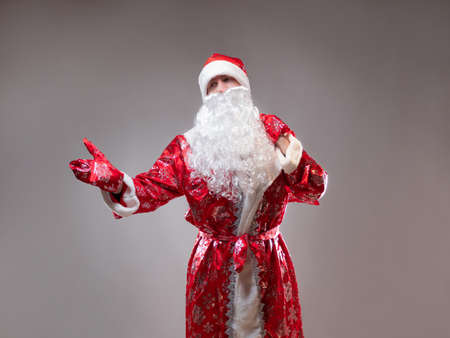 Santa Claus is a traditional Russian grandfather in a red caftan with a bag of gifts. A man in a New Years costume. Childrens holiday, New Years gifts for everyoneの写真素材