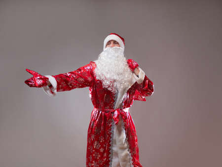 Santa Claus is a traditional Russian grandfather in a red caftan with a bag of gifts. A man in a New Years costume. Childrens holiday, New Years gifts for everyoneの写真素材