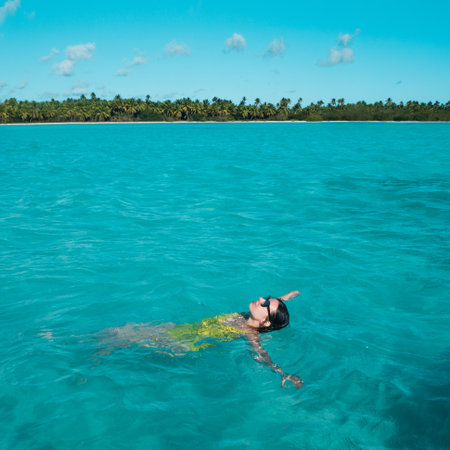 young woman in a one-piece yellow swimsuit floats on the surface of the water. Brunette girl relaxes and bathes in the blue sea, relaxing by the seaの写真素材