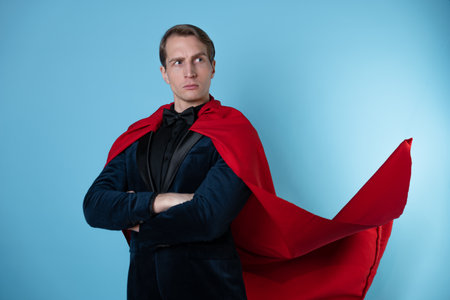 superhero stands in a heroic pose, a man in a business suit and a red cape. charismatic and successful business hero.の写真素材