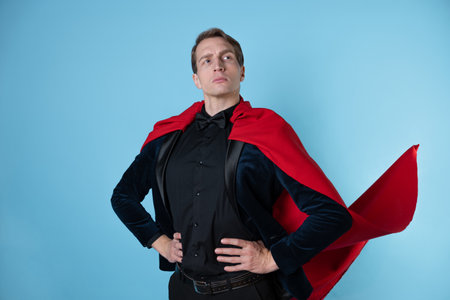 superhero stands in a heroic pose, a man in a business suit and a red cape. charismatic and successful business hero.の写真素材