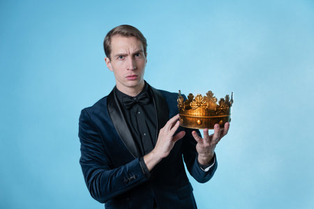 To become the best, the concept of a careerist. A young man in a business suit holds a crown in his hands.の写真素材