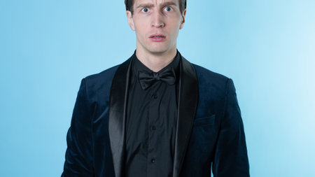 confused young man in a business suit, experiencing negative emotions,portrait on a blue backgroundの写真素材