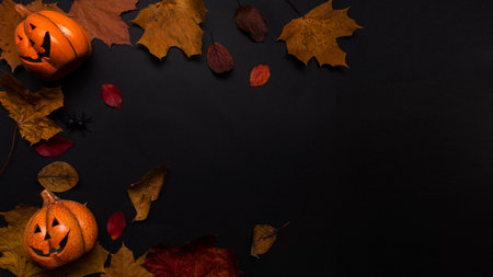Layout on the theme of the autumn Halloween holiday, funny pumpkins and red and yellow leaves, top view,copy the space in the center. Toy Jack lantern on a black backgroundの写真素材