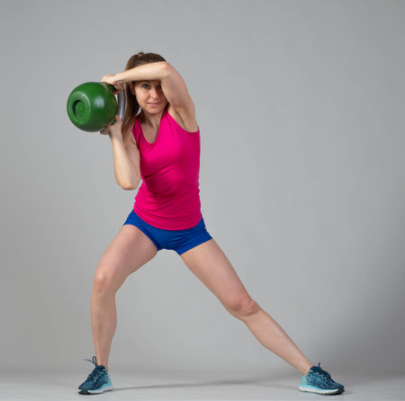 Training with kettlebells, a young athlete performs exercises with kettlebells, lunges with weightsの写真素材