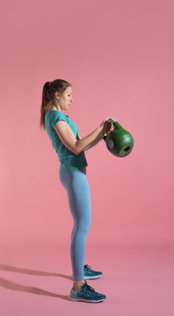 Training with kettlebells, a young athlete performs exercises with kettlebells, push kettlebells, frame-by-frame, pink backgroundの写真素材