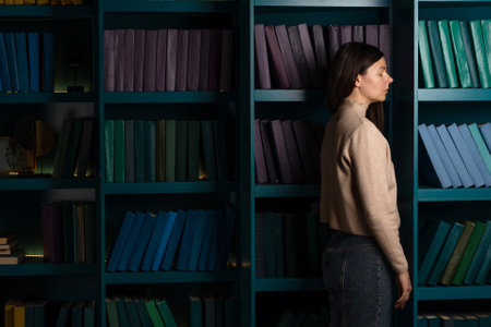 Exam stress, tired girl on the background of bookshelves. Natural sciences. A large amount of information. Student in the library, laconic minimalistic styleの写真素材