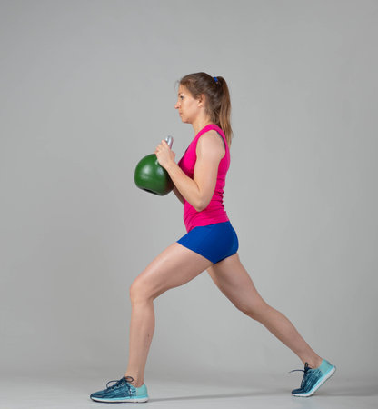 Training with kettlebells, a young athlete performs exercises with kettlebells, kettlebell lifting for the tone of the whole bodyの写真素材