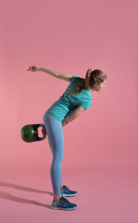 Training with kettlebells, a young athlete performs exercises with kettlebells, push kettlebells, frame-by-frame, pink backgroundの写真素材