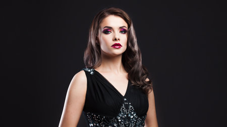 Gorgeous young brunette in a chic evening look. Scarlet lips and eye shadow, wave hair stylingの写真素材