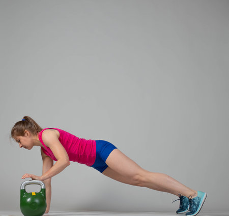 Training with kettlebells, a young athlete performs exercises with kettlebells, kettlebell lifting for the tone of the whole bodyの写真素材
