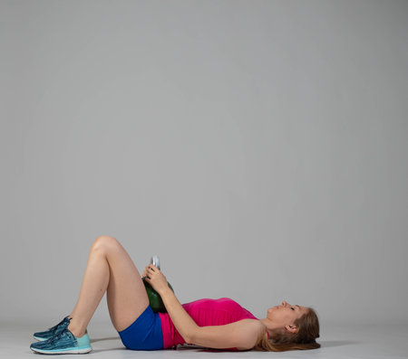 Training with kettlebells, a young athlete performs exercises with kettlebells, pushing the kettlebell up from the lying positionの写真素材
