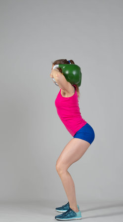 Training with kettlebells, a young athlete performs exercises with kettlebells, kettlebell lifting for the tone of the whole bodyの写真素材