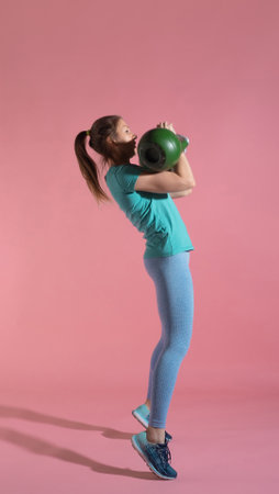 Training with kettlebells, a young athlete performs exercises with kettlebells, push kettlebells, frame-by-frame, pink backgroundの写真素材