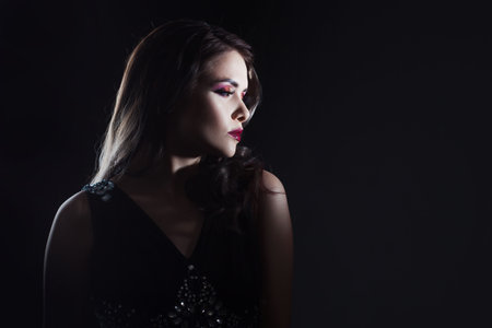 luxurious and mysterious beauty in Noir style, a portrait on a black background, deep shadows and a mysterious look. Fatal lady close-upの写真素材