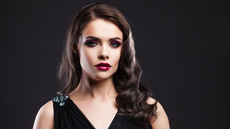 Gorgeous young brunette in a chic evening look. Scarlet lips and eye shadow, wave hair stylingの写真素材
