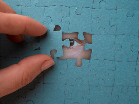 Hidden identity, concept. Puzzle pieces hide a womans face, a look through the holeの写真素材