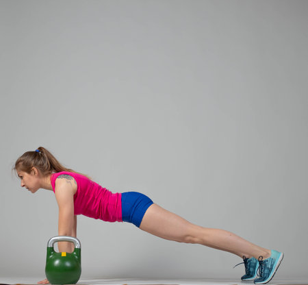 Training with kettlebells, a young athlete performs exercises with kettlebells, kettlebell lifting for the tone of the whole bodyの写真素材