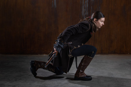 A noble robber with a revolver in a squat, preparing to attack. A woman in a retro fantasy outfit on the background of a textured rusty wallの写真素材