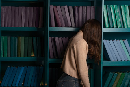 Depression and chronic fatigue. Cognitive overload from an overabundance of news and information noise, concept. An apathetic woman stands with her face buried in bookshelves.の写真素材