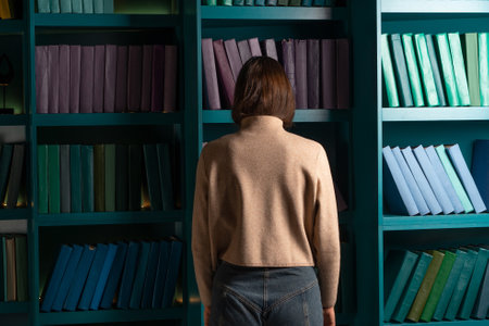 Depression and chronic fatigue. Cognitive overload from an overabundance of news and information noise, concept. An apathetic woman stands with her face buried in bookshelves.の写真素材