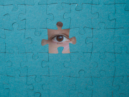 Hidden identity, concept. Puzzle pieces hide a womans face, a look through the holeの写真素材