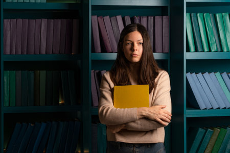 Higher education, training in complex specialties, concept. Natural sciences. A large amount of information. Student in the library against the background of bookshelves, laconic minimalistic styleの写真素材