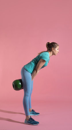 Training with kettlebells, a young athlete performs exercises with kettlebells, push kettlebells, frame-by-frame, pink backgroundの写真素材