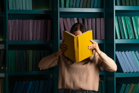 Higher education, training in complex specialties, concept. Natural sciences. A large amount of information. Student in the library against the background of bookshelves, laconic minimalistic styleの写真素材