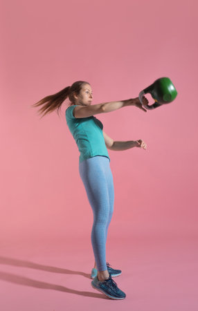 Training with kettlebells, a young athlete performs exercises with kettlebells, push kettlebells, frame-by-frame, pink backgroundの写真素材