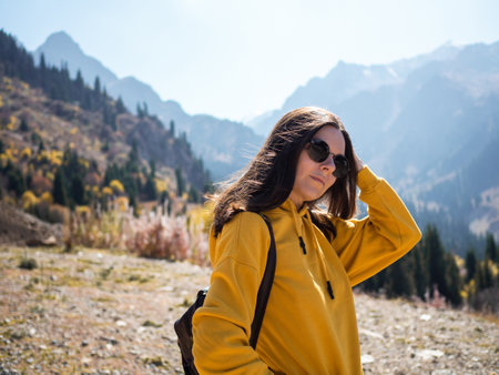 A young female tourist in a yellow hoodie on the background of nature, mountain landscape