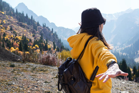 A young female tourist in a yellow hoodie on the background of nature, mountain landscape