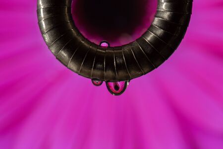 metal necklace with drops of water and vision of a flower in the background that shines through the drops.の写真素材