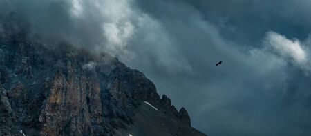 Eagle soaring near rock Zagedan. Dramatic overcast sky. Caucasus mountains. Karachay-Cherkessia. Russia.の写真素材